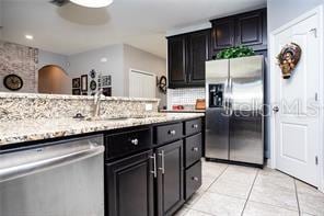 kitchen featuring decorative backsplash, appliances with stainless steel finishes, light tile patterned flooring, and sink