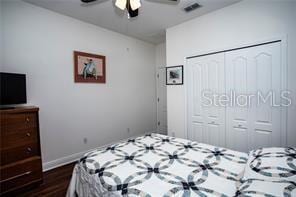 bedroom with ceiling fan, dark hardwood / wood-style floors, and a closet