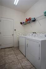 clothes washing area featuring washer and clothes dryer and light tile patterned flooring