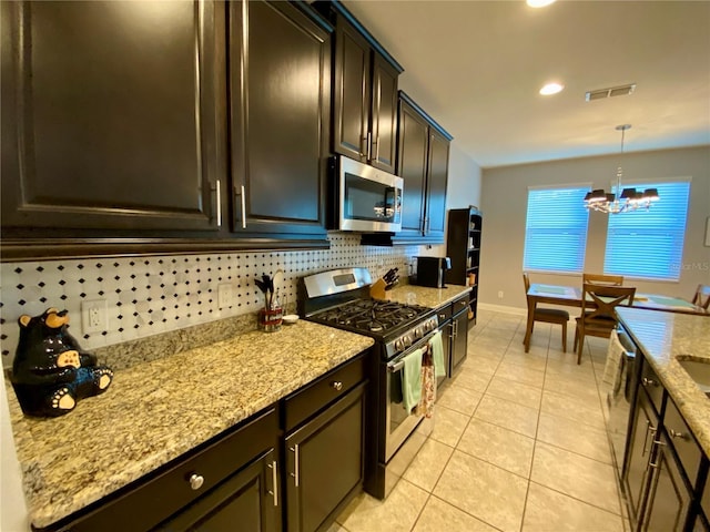 kitchen with backsplash, an inviting chandelier, hanging light fixtures, light tile patterned floors, and stainless steel appliances