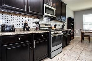 kitchen featuring decorative backsplash, light tile patterned flooring, and stainless steel appliances