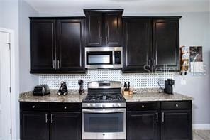 kitchen featuring stainless steel appliances, light stone counters, and tasteful backsplash