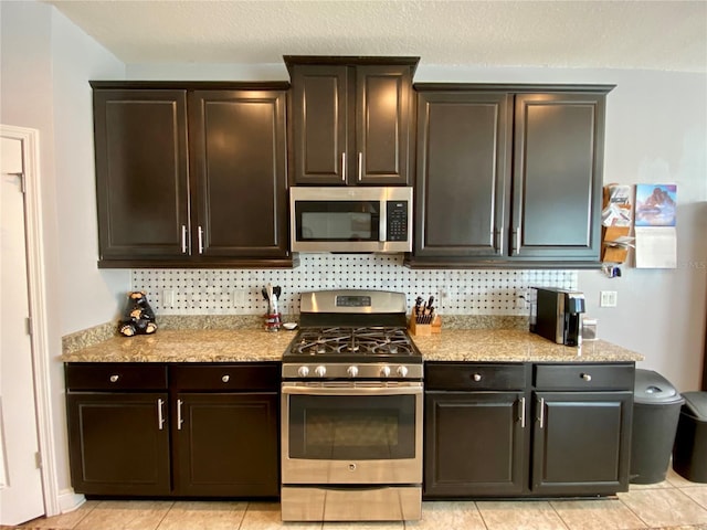 kitchen featuring tasteful backsplash, dark brown cabinets, light tile patterned flooring, and stainless steel appliances