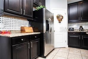 kitchen with backsplash, stainless steel fridge with ice dispenser, and light tile patterned floors