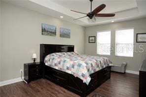 bedroom with a tray ceiling, ceiling fan, and dark hardwood / wood-style floors