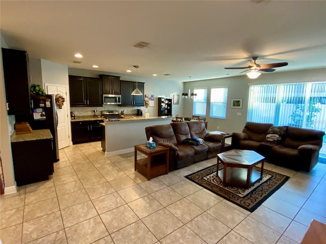 tiled living room with ceiling fan with notable chandelier