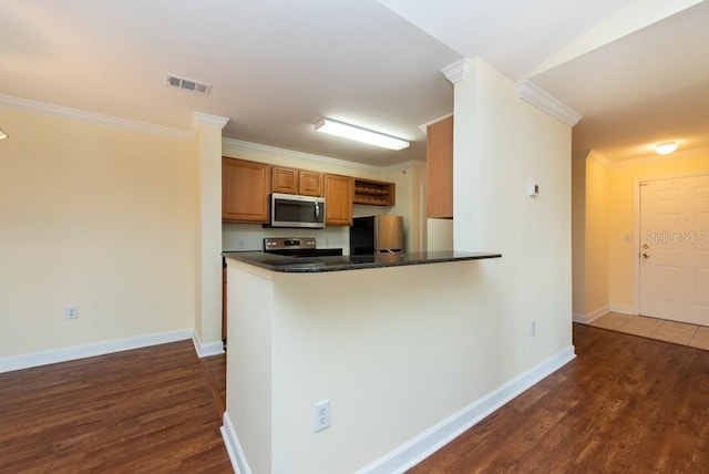 kitchen with kitchen peninsula, ornamental molding, stainless steel appliances, and dark hardwood / wood-style flooring