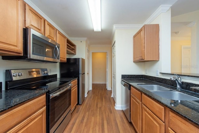 kitchen with stainless steel appliances, dark stone counters, sink, crown molding, and light hardwood / wood-style floors