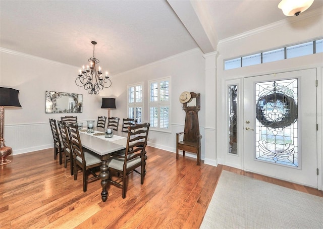 dining room featuring wood-type flooring, crown molding, a notable chandelier, and beam ceiling