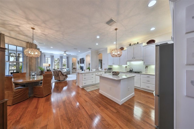 kitchen with kitchen peninsula, white cabinets, stainless steel appliances, and decorative light fixtures