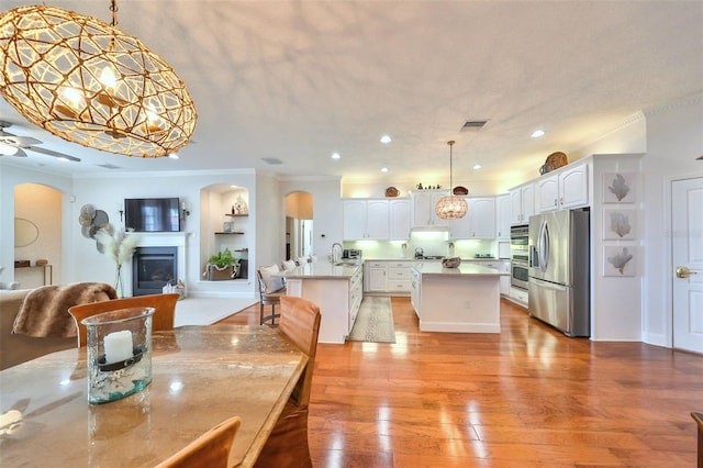 dining room featuring ceiling fan, ornamental molding, sink, and light hardwood / wood-style flooring