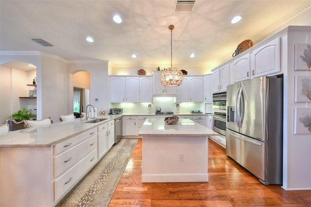 kitchen with white cabinets, sink, hanging light fixtures, kitchen peninsula, and stainless steel appliances