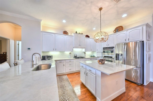 kitchen featuring sink, hanging light fixtures, light stone counters, white cabinets, and appliances with stainless steel finishes