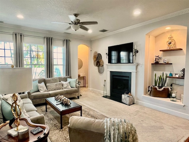 carpeted living room with ceiling fan, ornamental molding, and a textured ceiling