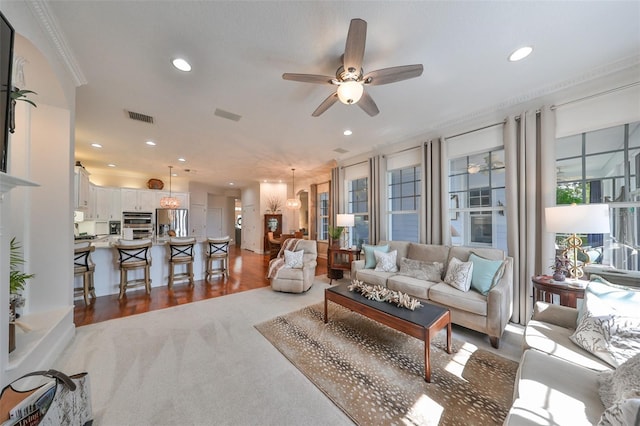 carpeted living room featuring ceiling fan and crown molding