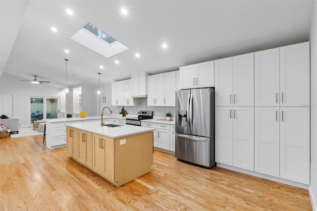 kitchen featuring ceiling fan, sink, hanging light fixtures, stainless steel appliances, and a center island with sink