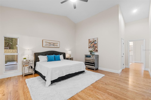 bedroom with ceiling fan, high vaulted ceiling, and light hardwood / wood-style flooring