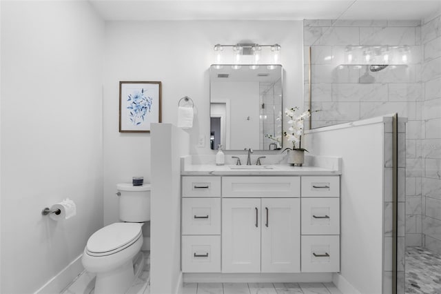 bathroom featuring a tile shower, vanity, and toilet