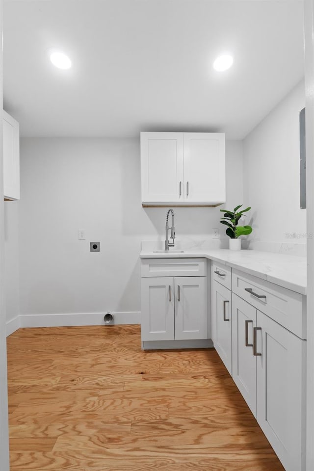 washroom featuring electric dryer hookup, sink, and light hardwood / wood-style flooring