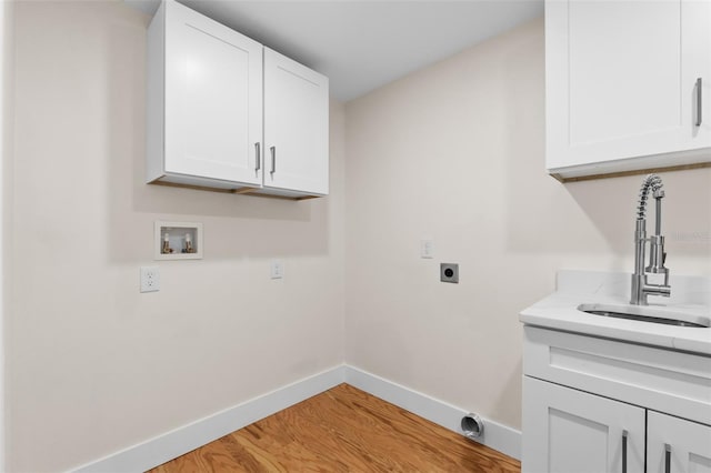 clothes washing area with sink, cabinets, washer hookup, electric dryer hookup, and light hardwood / wood-style flooring