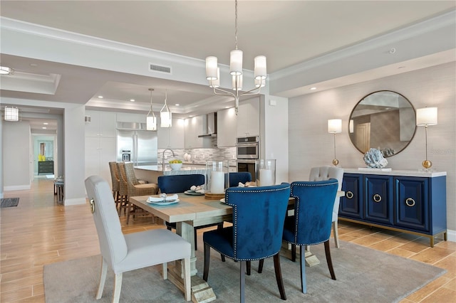 dining space with light hardwood / wood-style flooring, a chandelier, a tray ceiling, and crown molding