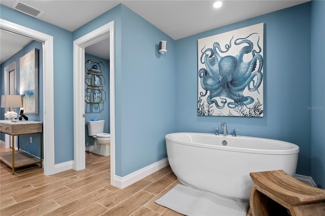 bathroom featuring toilet, wood-type flooring, and a washtub