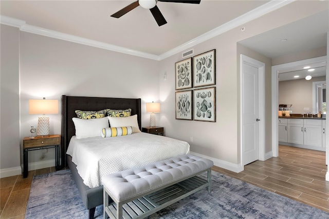 bedroom featuring ceiling fan, wood-type flooring, ensuite bathroom, crown molding, and sink