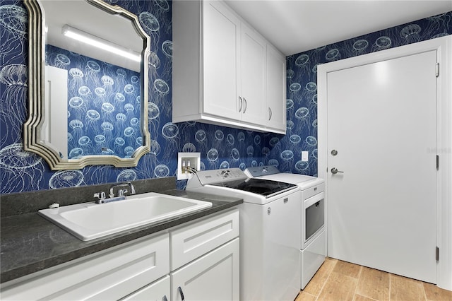 laundry room featuring cabinets, sink, washing machine and clothes dryer, and light wood-type flooring