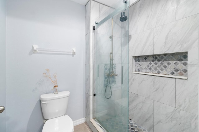 bathroom featuring a shower with door and toilet