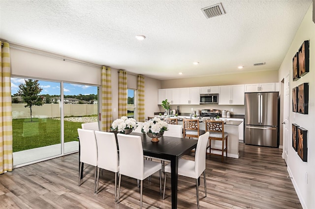 dining space featuring a textured ceiling and hardwood / wood-style floors