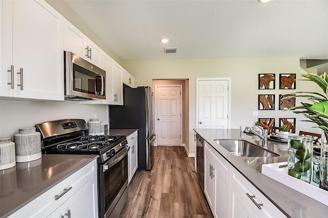 kitchen featuring sink, a textured ceiling, stainless steel appliances, white cabinets, and dark hardwood / wood-style floors