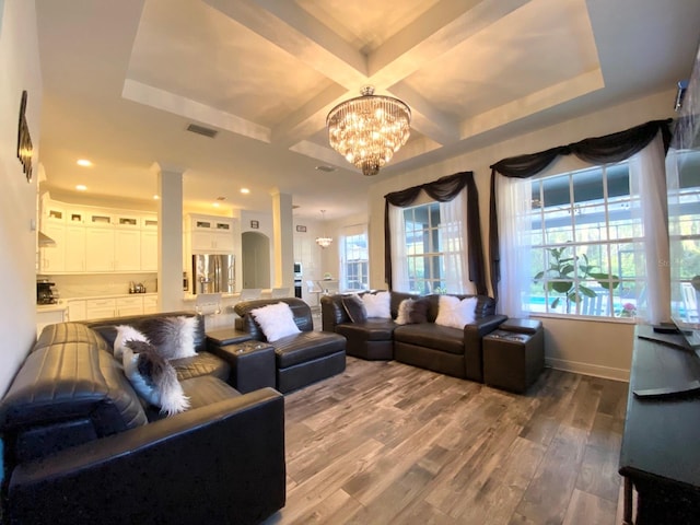 living room with ornate columns, coffered ceiling, beam ceiling, a notable chandelier, and hardwood / wood-style floors