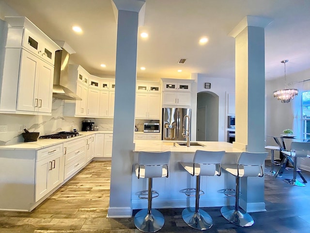 kitchen with white cabinets, wall chimney exhaust hood, sink, and light hardwood / wood-style flooring