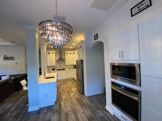 kitchen featuring white cabinetry, sink, wall chimney range hood, dark hardwood / wood-style flooring, and appliances with stainless steel finishes