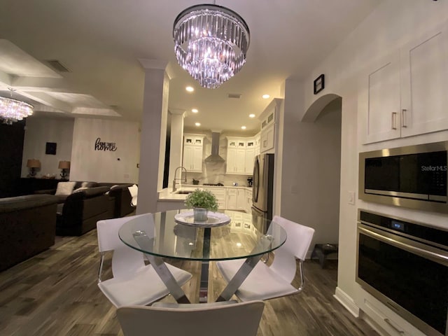 dining area with sink, dark hardwood / wood-style floors, and an inviting chandelier