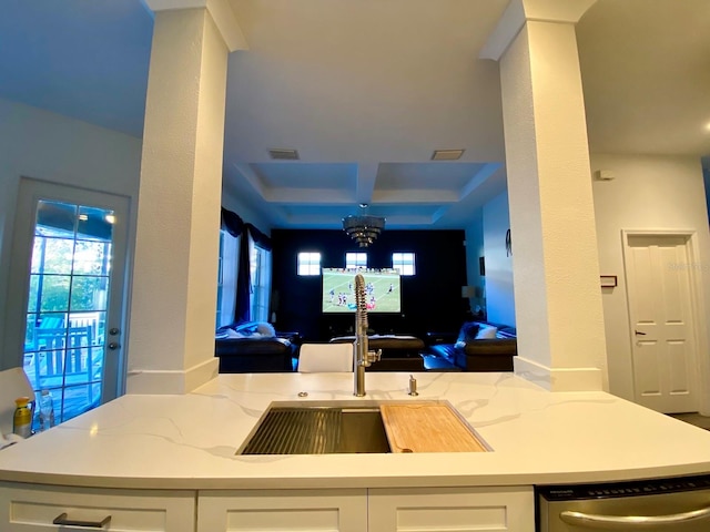 kitchen featuring light stone counters, stainless steel dishwasher, a tray ceiling, sink, and white cabinets