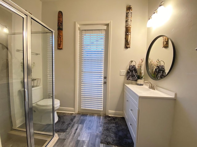 bathroom with hardwood / wood-style floors, vanity, a shower with shower door, and toilet