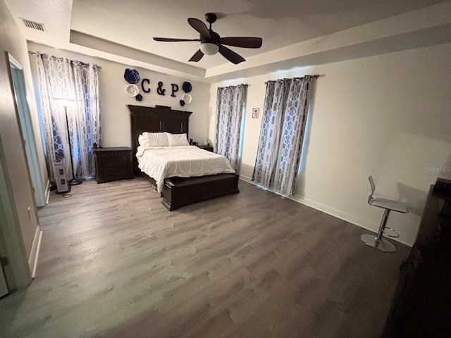 bedroom with a raised ceiling, ceiling fan, and hardwood / wood-style floors