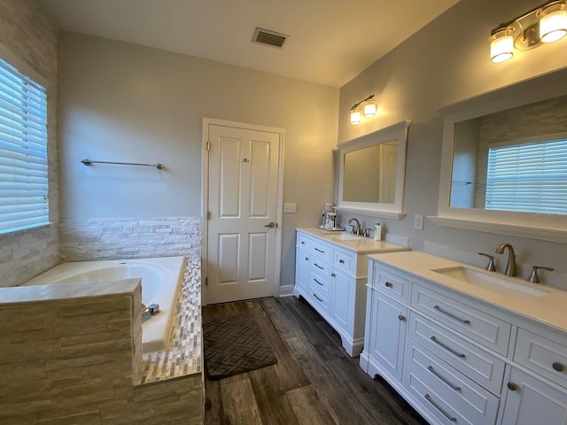 bathroom with hardwood / wood-style flooring, vanity, and a bath