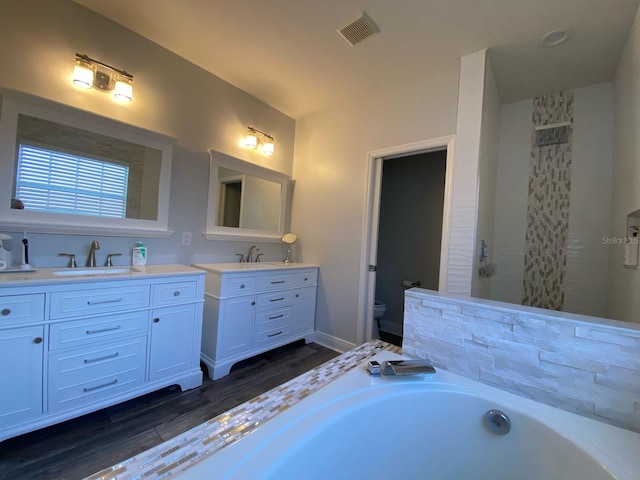 full bathroom featuring wood-type flooring, vanity, shower with separate bathtub, and toilet