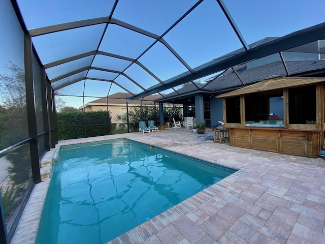 view of swimming pool featuring glass enclosure and a patio area