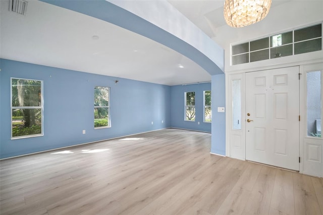 foyer with light wood-type flooring, an inviting chandelier, and a wealth of natural light