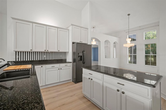 kitchen with sink, stainless steel fridge with ice dispenser, decorative light fixtures, white cabinets, and light wood-type flooring