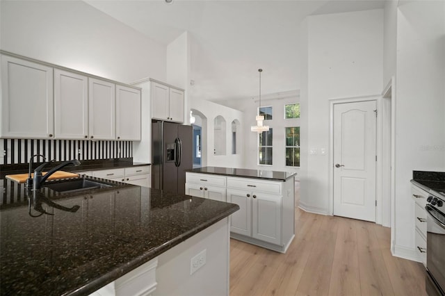 kitchen with stainless steel fridge with ice dispenser, white cabinets, decorative light fixtures, and light wood-type flooring