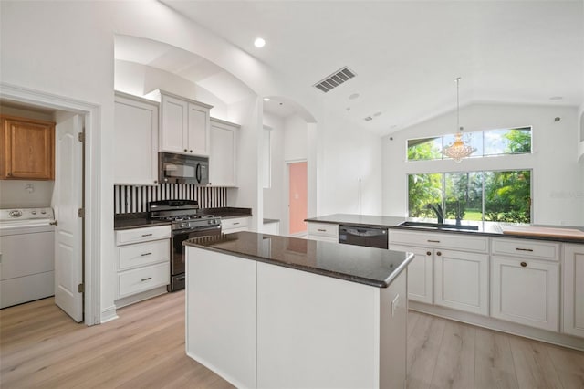 kitchen with sink, black appliances, white cabinets, washer / dryer, and a kitchen island