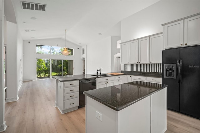 kitchen featuring a center island, black appliances, sink, vaulted ceiling, and white cabinetry