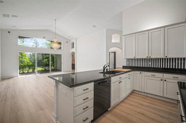 kitchen featuring sink, black dishwasher, kitchen peninsula, dark stone counters, and light hardwood / wood-style floors