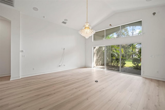 unfurnished living room with high vaulted ceiling, light hardwood / wood-style flooring, and a notable chandelier