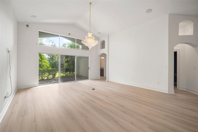 unfurnished living room with light hardwood / wood-style flooring, high vaulted ceiling, and an inviting chandelier