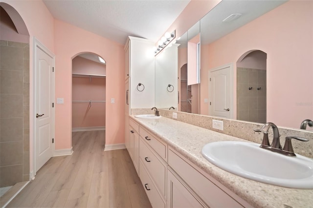 bathroom featuring tiled shower, wood-type flooring, and vanity